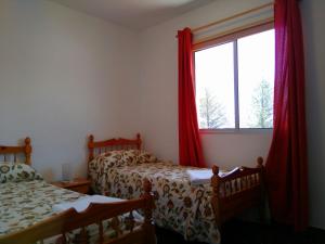 圣地亚哥海滩Apartamentos Noda的一间卧室设有两张床,窗户配有红色窗帘