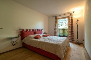 泰塞罗Casa Fam.Barbolini的一间卧室配有一张带红色枕头的床和一扇窗户