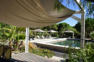 圣特罗佩Campagne les Jumeaux的度假村内带椅子和遮阳伞的游泳池