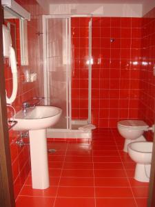 TitoSanta Loja Hotel Residence的红色瓷砖浴室设有2个卫生间和淋浴