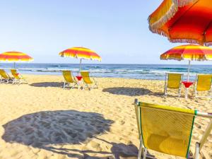 卡尼亚诺瓦拉诺Villaggio Camping Rancho的海滩上的一组椅子和遮阳伞