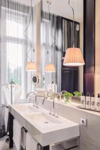 柏林柏林动物园酒店的浴室设有白色水槽和两盏灯。