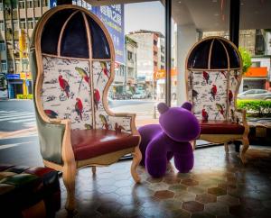 高雄秝芯旅店驳二馆的两把椅子旁边坐着紫色泰迪熊