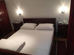 克拉列沃Vila Lux Milikic的一间卧室配有一张带两个白色枕头的床和一部电话
