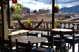 昆卡El Cafecito Hostel Cuenca的阳台配有桌椅和吊床。