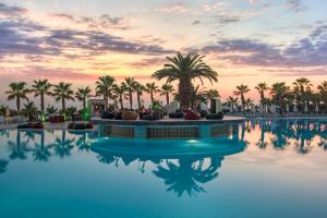 欧库卡拉Botanik Hotel的棕榈树泳池和日落背景
