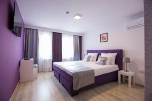 图兹拉Heartland City B&B的一间卧室配有紫色的床和一台平面电视
