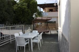 托雷圣乔万尼乌Villetta Angela的庭院里配有白色的桌椅和遮阳伞