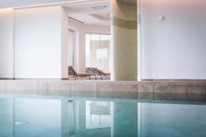 瓦尔道拉科隆普拉茨水晶度假酒店的大楼内一个带两把椅子的游泳池