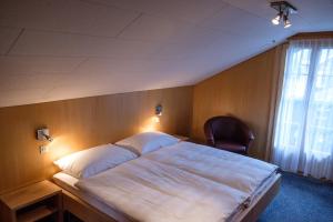 伦克加尼阿尔盆鲁酒店的一间卧室配有一张大床和一把椅子