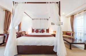 河内La Dolce Vita Hotel的卧室配有一张带白色窗帘的大床