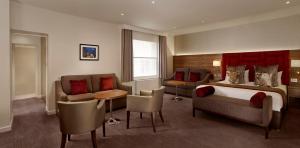 伦敦诺福克塔帕丁顿酒店的酒店客房配有一张床、一张沙发和椅子。
