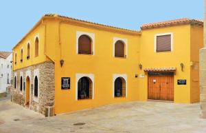 奥罗佩萨Casa Rural El Infante的黄色的建筑,设有大门和车库