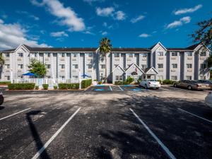 棕榈海岸Microtel Inn & Suites by Wyndham Palm Coast I-95的一座白色的大建筑,汽车停在停车场