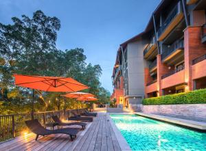 尖竹汶Rimnaam Klangchan Hotel - SHA Plus的一座带椅子和遮阳伞的游泳池位于一座建筑旁边