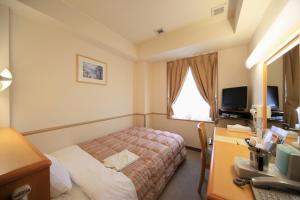 土浦市Crown Hills Tsuchiuraekihigashi的酒店客房配有一张床和一张带电脑的书桌