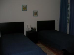 雷根古什-迪蒙萨拉什Reguengos Hotel的一间卧室设有两张床和一张桌子上的台灯。