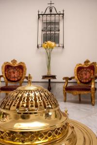 塞维利亚Apartamentos "El Escondite de María"的一张带椅子和花瓶的房间的金桌