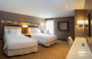 波哥大Mercure Bogota Calle 100的酒店客房设有两张床和一张桌子。