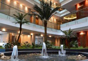 基加利Ubumwe Grande Hotel的酒店大堂设有喷泉和棕榈树