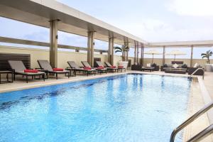 吉达沙欣吉达中心罗塔纳酒店的一个带躺椅和桌子的酒店游泳池