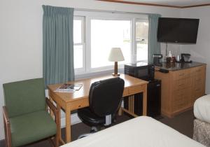 MachiasThe Bluebird Motel Maine的酒店客房配有书桌、椅子和床。