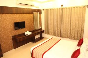 舍地Hotel Sai Ramanand的酒店客房,配有床和电视