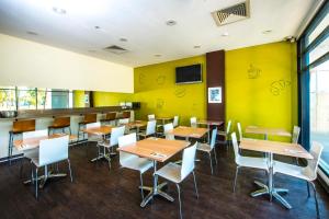 悉尼宜必思快捷酒店 - 悉尼奥林匹克公园的餐厅设有桌椅和黄色的墙壁