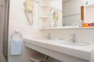 Gallbrunn朗格斯霍夫穆尔酒店的白色的浴室设有两个盥洗盆和镜子
