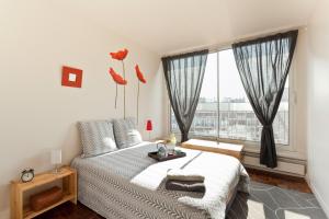 巴黎艾美公寓的一间卧室设有一张床和一个大窗户