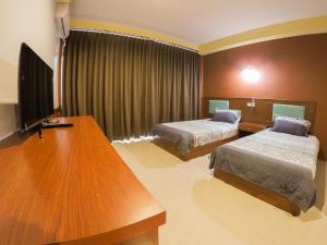 卡伦海滩女士之家旅馆的客房设有两张床和一张书桌及一台电视。