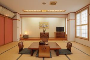 野沢野泽温泉乌托邦酒店的客厅配有桌椅和电视。
