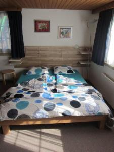 阿彭策尔弗里恩沃奈格茵尔恩酒店的一间卧室配有一张带蓝色和白色棉被的床