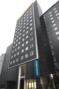 东京相铁Fresa Inn银座七丁目酒店的一座高大的黑色建筑,上面有标志