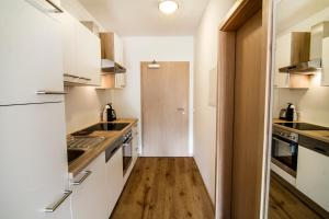皮森多夫Oscar & Sons Apartments的厨房铺有木地板,配有白色橱柜。