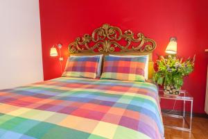 乌迪内Toti Apartment的一间卧室配有一张色彩缤纷的床和红色的墙壁