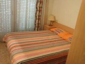 布拉内斯Apartamentos Montserrat的一间卧室配有一张带彩色毯子的床