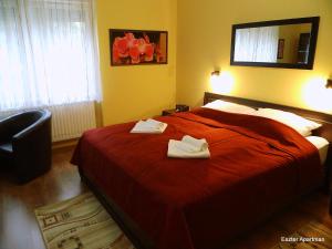 贝凯什乔包Eszter Apartman的一间卧室配有红色的床和2条毛巾