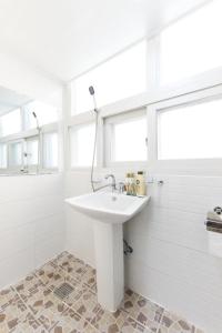 首尔克里宾馆的白色的浴室设有水槽和淋浴。