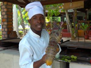 Grand-PopoHotel Village Vacances Awale Plage的厨师用棍子拿着龙虾