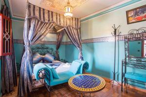 马拉喀什里亚德哈姆扎住宿加早餐旅馆的一间卧室配有一张天蓬床、一把椅子和一张桌子