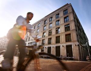 柏林Hotel AMANO Rooms & Apartments的一名在建筑物前骑滑板的人