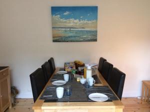 霍伊莱克Seaways Cottage Hoylake的餐桌、椅子和墙上的绘画