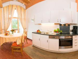 希洛谢克嘎斯特豪斯布切尔酒店的一间厨房,内设白色橱柜和一张桌子