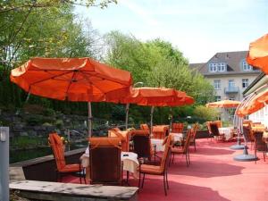 伊瑟隆校园花园商务酒店 的庭院配有桌椅和橙色遮阳伞。