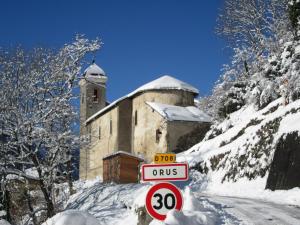 OrusGîte Orus的一条有雪覆盖的道路,后面有一座建筑