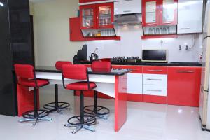 那格浦尔Shivam Apartment的厨房配有红色和白色的橱柜和红色凳子