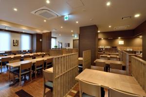 富士市Hotel Route-Inn Fuji Chuo Koen Higashi的用餐室配有木桌和椅子