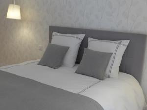 孔堡Maison de Luciné的一张带白色床单和灰色枕头的床