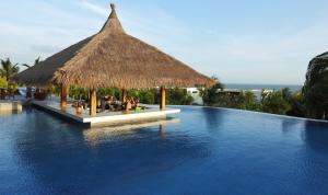 美奈海崖度假酒店的一个带茅草屋顶的度假游泳池